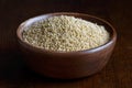 Dry millet in brown wooden bowl isolated on dark.