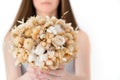 Dry mixed bouquet of different flowers in hands of unrecognisable woman on white background. Giving present for holiday