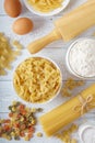 Dry mixed pasta with spaghetti and ingredients for pasta on wood table. Royalty Free Stock Photo