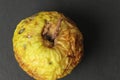 a dry old apple wrinkled on a black background. Ugly foods. Bad spoiled fruit food