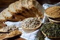 Dry organic sunflower seeds in wooden bowl over blur whole wheat bread, golden flax and pumpkin seed Royalty Free Stock Photo