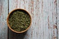 Dry parsley in a wooden bowl on a wooden table.