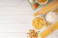 Dry pasta with spaghetti and ingredients for pasta on white wood