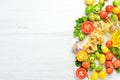 Dry pasta, tomatoes, greens, oil and ingredients. Italian traditional cuisine. Fresh vegetables. Top view. Royalty Free Stock Photo