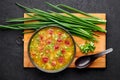 Dry Yellow Pea Soup with meat sausages, potato, green onions and sesame in black bowl at dark slate background Royalty Free Stock Photo