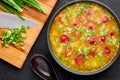 Dry Yellow Pea Soup with meat sausages, potato, green onions and sesame in black bowl at dark slate background Royalty Free Stock Photo