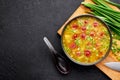 Dry Yellow Pea Soup with meat sausages, potato, green onions and sesame in black bowl at dark slate background Royalty Free Stock Photo