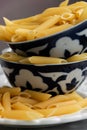 Dry penne pasta on blue vintage plate, whole uncooked ingredient