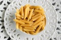 Dry penne pasta on blue white vintage plate, whole wheat uncooked ingredient