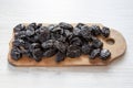 Dry prunes on rustic wooden board on a white wooden background, side view Royalty Free Stock Photo
