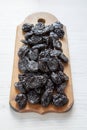 Dry prunes on rustic wooden board on a white wooden table, side view. Close-up Royalty Free Stock Photo