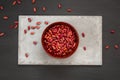 Dry beans in a brown bowl on a concrete tile on a dark background