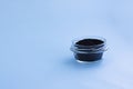 Dry raw sweet black basil seeds, other name tukhmaria or falooda or sabja in glass bowl on blue background with copy