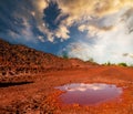 Dry red soil with puddle at sunset Royalty Free Stock Photo