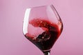 Dry red wine, splash in glass, pink background, defocused in mot