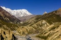 Almost dry river of nepal crosses a spectacular valley with the snowy annapurnas in the background and blue sky