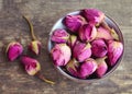 Dry rose buds flowers in a bowl on old wooden table.Healthy herbal drinks concept.Asian ingredient for aromatherapy tea. Royalty Free Stock Photo