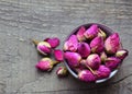 Dry rose buds flowers in a bowl on old wooden table.Healthy herbal drinks concept.Asian ingredient for aromatherapy tea. Royalty Free Stock Photo