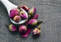 Dry rose buds flowers in a white spoon on old wooden table.Asian ingredient for aromatherapy herbal tea. Royalty Free Stock Photo