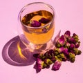 Tea with rose buds. Dry rose buds, a teacup on a pink background. dried rose buds on a pink surface.