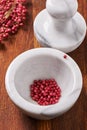 Dry rose pepper in white marble mortar next pestle Royalty Free Stock Photo