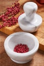 Dry rose pepper in white marble mortar next pestle Royalty Free Stock Photo