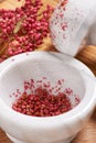 Dry rose pepper in white marble mortar next pestle Royalty Free Stock Photo