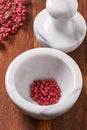 Dry rose pepper in white marble mortar next pestle Royalty Free Stock Photo