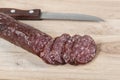 Dry salami sausage and knife on wooden board with slices