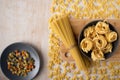 Dry spaghetti,fettuccine and sorprese in gray ceramic dishes on a bamboo cutting Board