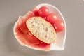 Dry Spanish ham, jamon, Italian ham, chopped layers with bread and cherry tomatoes on a white heart-shaped plate Royalty Free Stock Photo