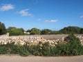 Dry stone wall running alongside a county road and fields in typical menorca countryside