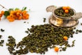 Dry tea herbs with orange berries and vintage silver tea strainer on white background