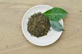 Dry tea in whte plate and fresh leaves on wooden table Royalty Free Stock Photo