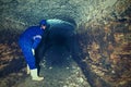 Dry tunnel, man worker in protective suite in underground. Mysterious dungeon tunnel Royalty Free Stock Photo