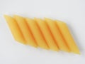 Dry uncooked yellow Italian penne pasta arranged neatly isolated on a white background. Royalty Free Stock Photo