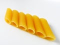 Dry uncooked yellow Italian penne pasta arranged neatly isolated on a white background. Royalty Free Stock Photo