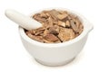 Closeup of Dry Vridha Daru barks in white ceramic mortar and pestle.