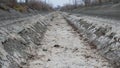 Dry water canal for irrigation, water transportation for fields, farms, dry land. Silt at the bottom of the channel made of