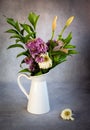 Dry wilted bouquet of flowers and green plants on a white vase and leaves on a grey vintage background. Royalty Free Stock Photo