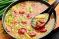 Dry Yellow Pea Soup with meat sausages, potato, green onions and sesame in black bowl Royalty Free Stock Photo