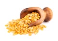 Dry yellow split peas in wooden scoop, isolated on white background. Halves of yellow legume peas.