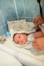 Drying of the child after a bath. bathing newborn. Cute newborn girl, a boy in a towel after a bath with his mother`s hands dryly Royalty Free Stock Photo