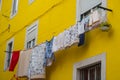 Drying clothes outside windows against yellow wall. Bright colorful building in Portugal. Traditional house exterior in Europe. Royalty Free Stock Photo