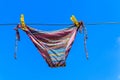 Drying female swimsuit hanging on a rope against blue sky