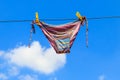 Drying female swimsuit hanging on rope against blue sky