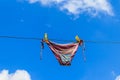Drying female swimsuit hanging on rope against blue sky