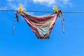 Drying female swimsuit hanging on rope against blue sky