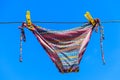 Drying female swimsuit hanging on rope against blue sky