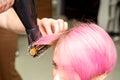 Drying short pink hair of young caucasian woman with a black hairdryer and black round brush by hands of a male Royalty Free Stock Photo